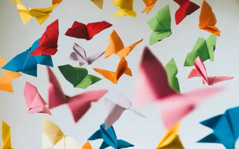 Papillons en origami multicolores flottant sur fond clair.