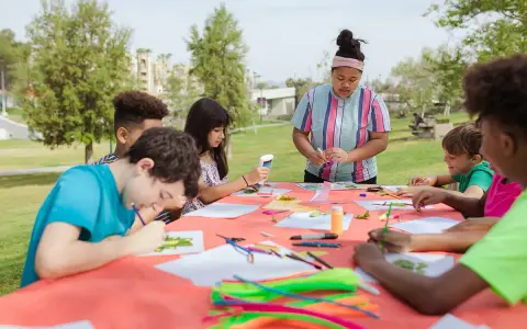 Des enfants créatifs participent à un atelier d'art en plein air, une activité typique d'un centre de loisirs ou d'un camp d'été, peut-être dans le cadre d'un programme ACM BAFA.