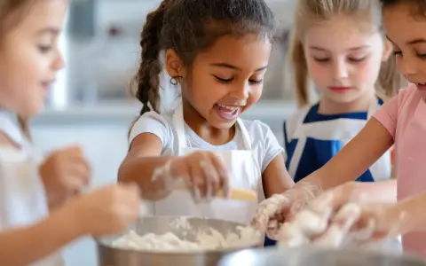 Des enfants joyeux préparent une recette dans des tabliers, les mains couvertes de farine.