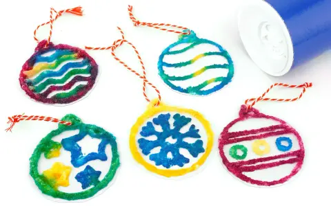 Cinq décorations colorées en sel, en forme de boules de Noël, avec des cordes rouges et blanches.