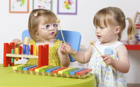Deux petites filles s'amusent avec un xylophone, explorant la musique et les activités manuelles.