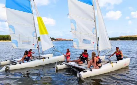 Des jeunes profitent d'une colonie de vacances voile, naviguant sur des catamarans par une journée ensoleillée.