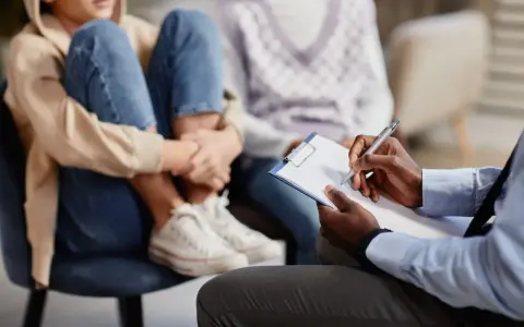 Un professionnel note des informations sur un jeune en difficulté, peut-être pour savoir comment faire une information préoccupante.
