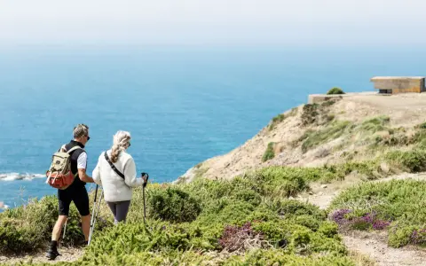 Couple randonnant sur les falaises de Jersey, profitant d'un séjour linguistique et d'une vue imprenable sur la mer.