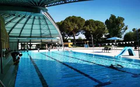 Piscine intérieure avec toboggan bleu, lignes de nage et quelques personnes.