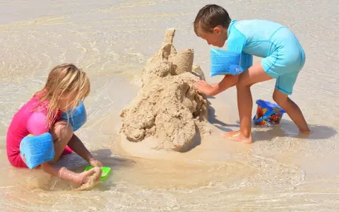 Enfants construisant un château de sable, une scène typique d'accueil centre de loisirs en bord de mer.