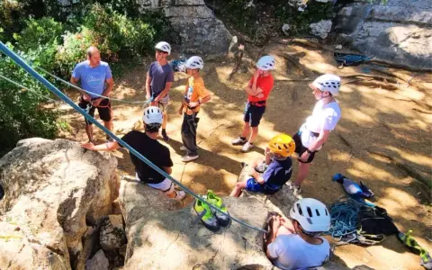 Des jeunes en pleine colonie de vacances escalade, casques blancs et jaunes, prêts pour l'aventure sur les rochers.