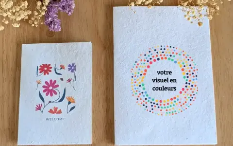 Deux carnets faits main sur fond de bois, décorés de fleurs et de points colorés.