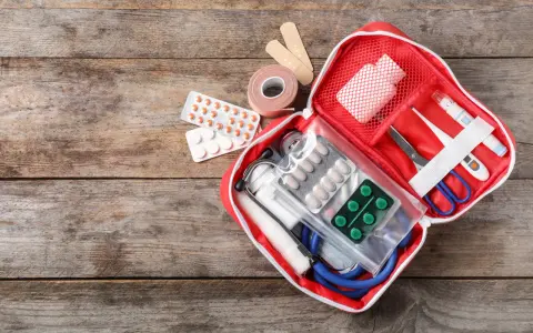 Trousse de secours pharmacie liste : pansements, rouleau de sparadrap, pilules, thermomètre, ciseaux, stéthoscope et masque.