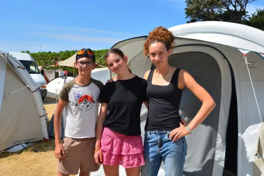 Trois jeunes amis souriants devant une tente. Si vous avez un problème, voici comment faire un signalement.