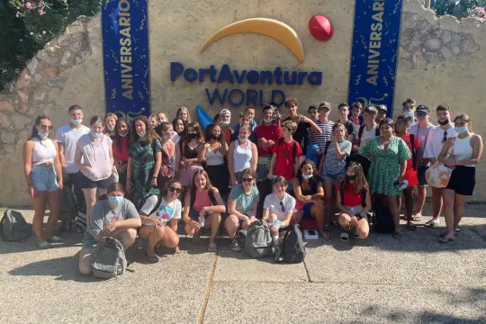 Un groupe de jeunes pose devant l'entrée de PortAventura World, un parc d'attractions en **Colo Espagne**. Ils semblent prêts pour une journée d'aventures.