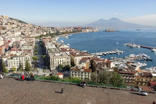 Vue panoramique de Naples avec le Vésuve en arrière-plan. Un port animé et des bâtiments colorés pour un voyage inoubliable.