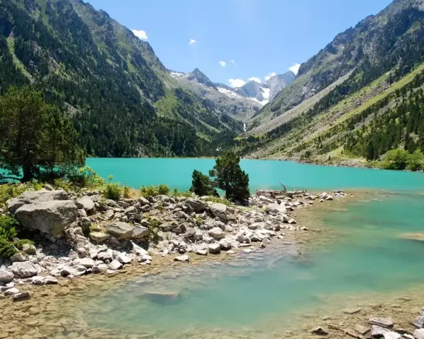 Un lac turquoise aux reflets émeraude, niché au cœur d'une vallée verdoyante des Pyrénées. Un paysage de carte postale, invitant à la contemplation.