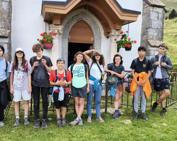 Groupe d'enfants en tenue de randonnée devant une petite église en montagne.