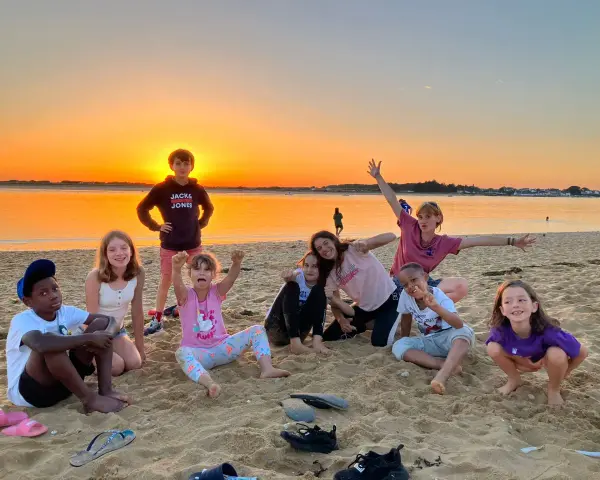 Groupe d'enfants joyeux sur une plage au coucher du soleil.