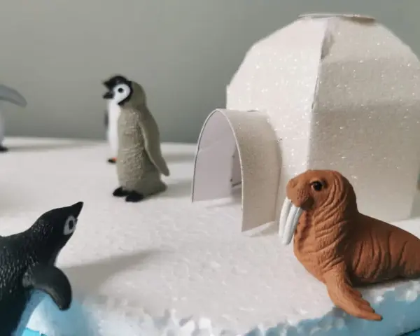 Maquette d'igloo blanc scintillant avec des figurines de phoques et de morses sur un décor de glace.