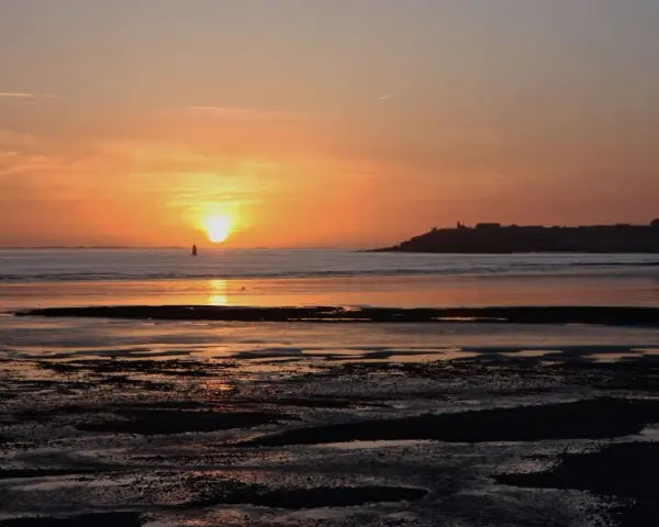 Coucher de soleil sur la mer à Saint-Pair-sur-Mer. La lumière dorée illumine le ciel et l'eau, invitant à la contemplation.