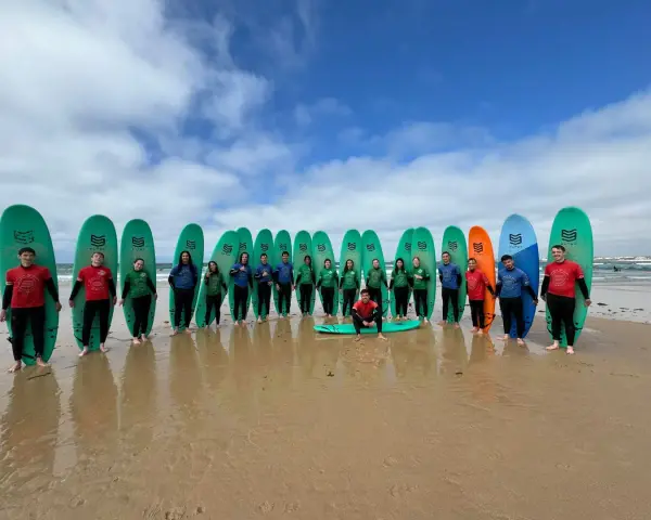 Groupe de jeunes souriants avec des planches de surf sur une plage.