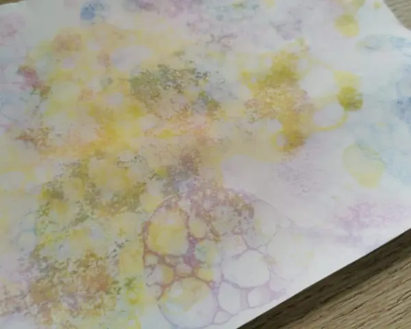 Peinture à bulles colorée sur papier blanc, avec des formes rondes et des éclaboussures.