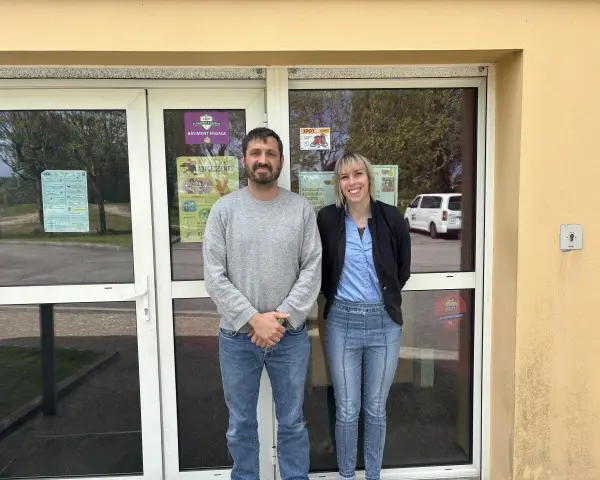 Le directeur du centre de loisirs et une collègue souriants devant l'entrée.
