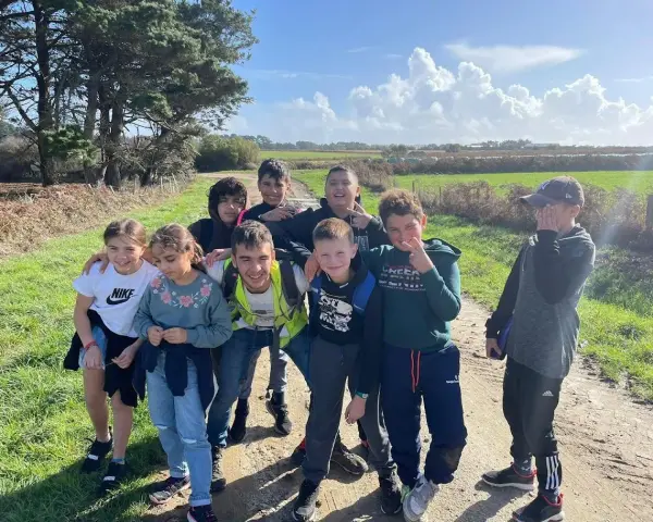 Groupe d'enfants souriants sur un chemin de terre, par une journée ensoleillée.