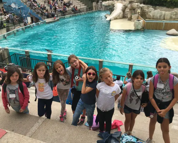 Des enfants en colonie de vacances en Île-de-France s'amusent devant un bassin de spectacle aquatique, faisant des grimaces.