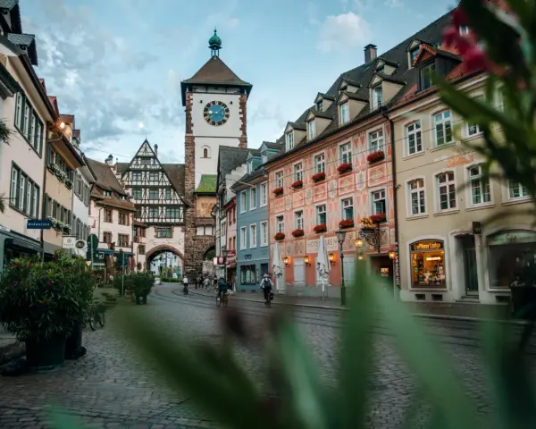 Vue d'une rue pavée à Fribourg-en-Brisgau avec une tour à horloge et des bâtiments colorés.