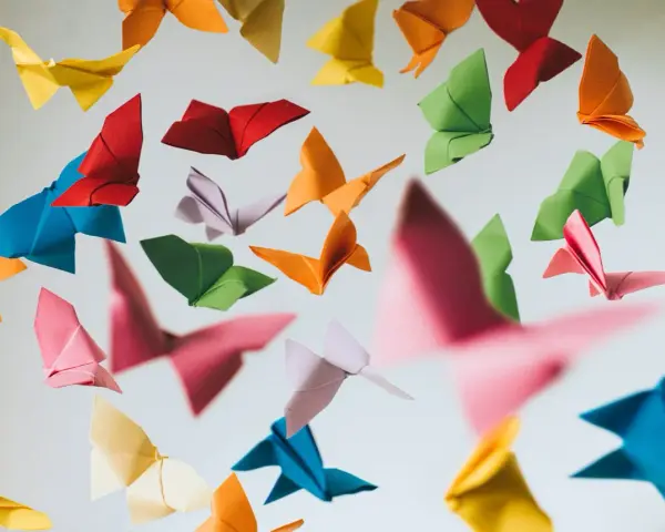 Papillons en origami multicolores flottant sur fond clair.