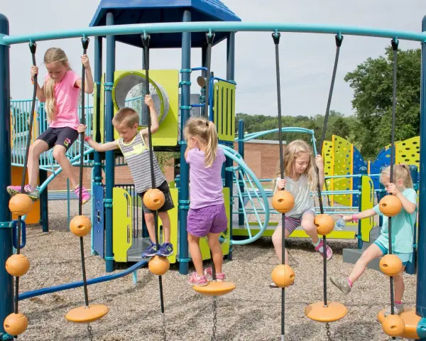 Enfants jouant sur une structure d'escalade avec des cordes et des balles oranges.