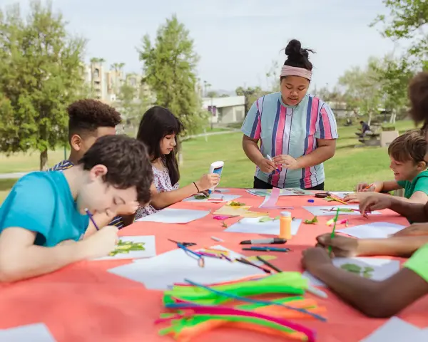 Des enfants créatifs participent à un atelier d'art en plein air, une activité typique d'un centre de loisirs ou d'un camp d'été, peut-être dans le cadre d'un programme ACM BAFA.