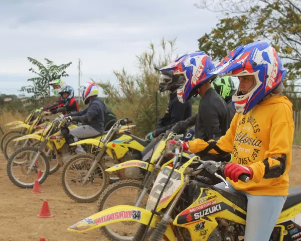 Jeunes pilotes prêts pour une course de moto cross. Casques colorés et motos jaunes alignées.