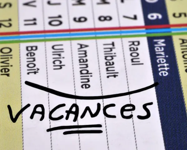 Calendrier avec noms et le mot "VACANCES" écrit à la main.
