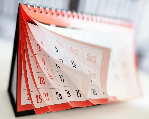 Calendrier de bureau avec pages qui tournent, montrant des dates.