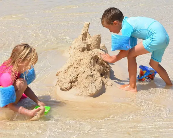 Enfants construisant un château de sable, une scène typique d'accueil centre de loisirs en bord de mer.