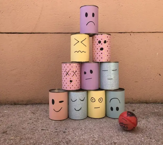 Pyramide de boîtes décorées de visages pour une kermesse chamboule tout. Un dessin amusant prêt à être renversé !