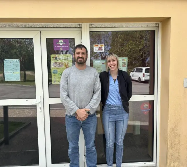 Le directeur du centre de loisirs et une collègue souriants devant l'entrée.