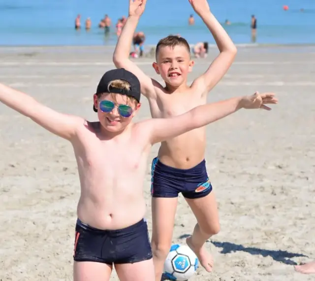 Enfants joyeux jouant au ballon sur une plage du colo sud de la France.