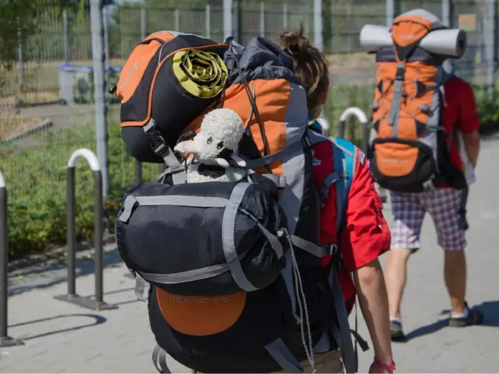 Deux jeunes partent en camp de scout, chargés de leurs sacs à dos. Un doudou mouton est accroché au sac de devant.