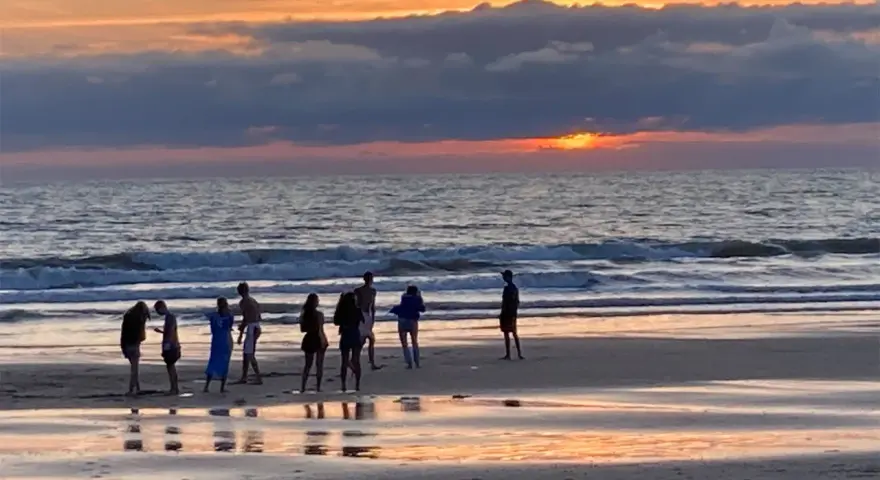 Coucher de soleil sur une plage avec des silhouettes de personnes.
