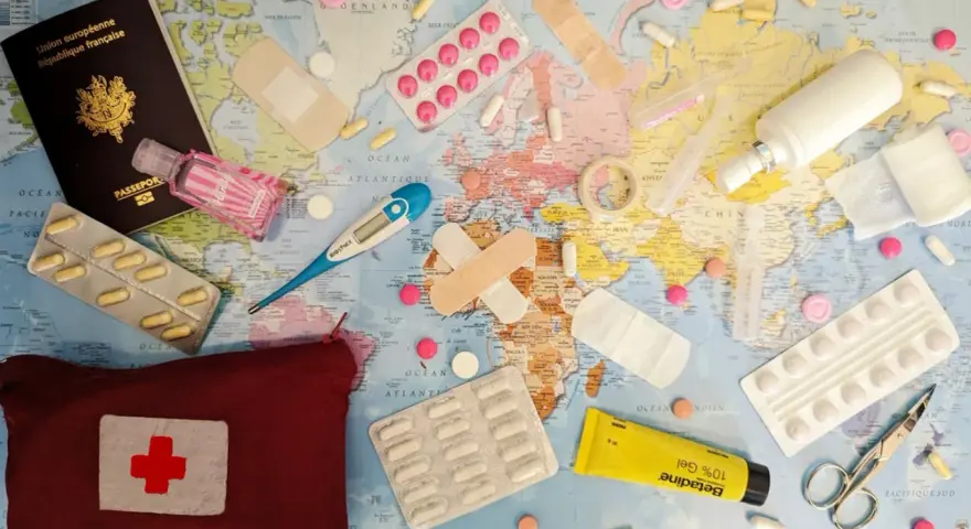 Une trousse de secours prête pour un voyage autour du monde : passeport, pansements, thermomètre, pilules, désinfectant et crème.