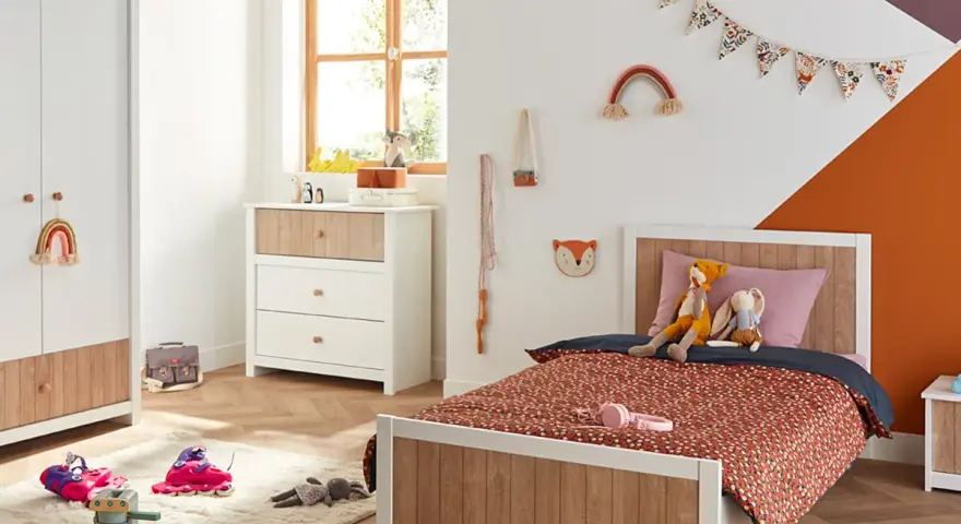 Chambre d'enfant décorée avec un lit, une commode, une armoire et des jouets.