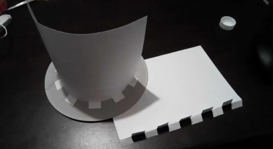 Chapeau en carton en cours de création, avec des pièces découpées et un patron.