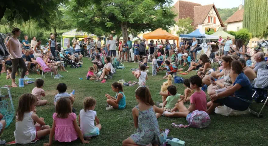 Une foule joyeuse, petits et grands, profite d'une fête de village. Une belle idée animation fête de village, avec des stands et des gens assis sur l'herbe.