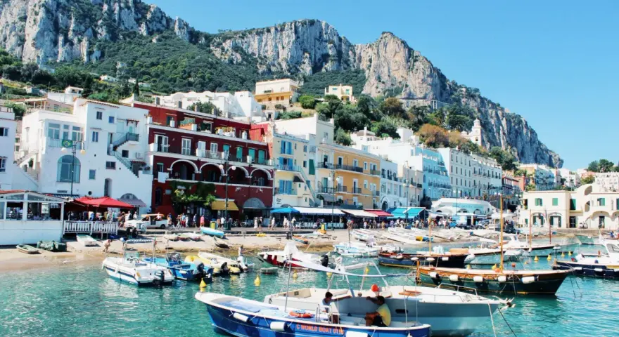 Vue pittoresque de Capri, un joyau pour votre naples voyage. Bateaux colorés dans une eau turquoise, face aux maisons et aux falaises majestueuses.