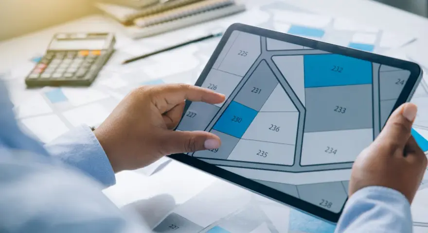 Main tenant examine un plan sur tablette, calculatrice et documents à proximité. Un contrat CEE avis est en cours de validation.