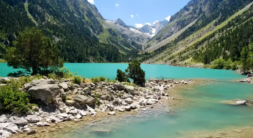 Un lac turquoise aux reflets émeraude, niché au cœur d'une vallée verdoyante des Pyrénées. Un paysage de carte postale, invitant à la contemplation.