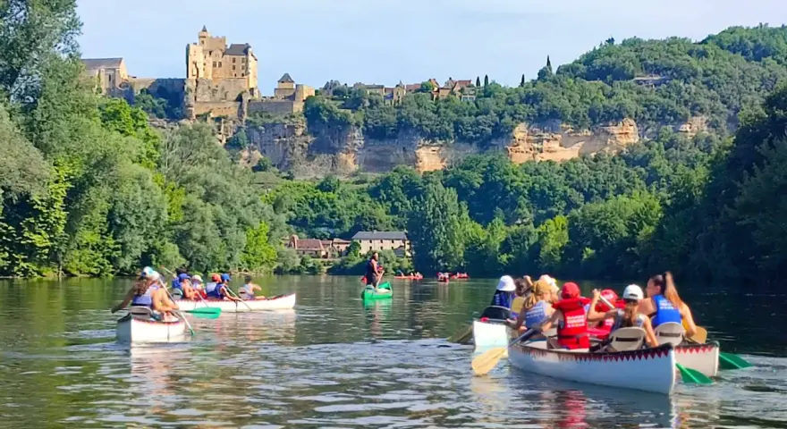 Des gens en canoë sur une rivière, avec un château en arrière-plan.