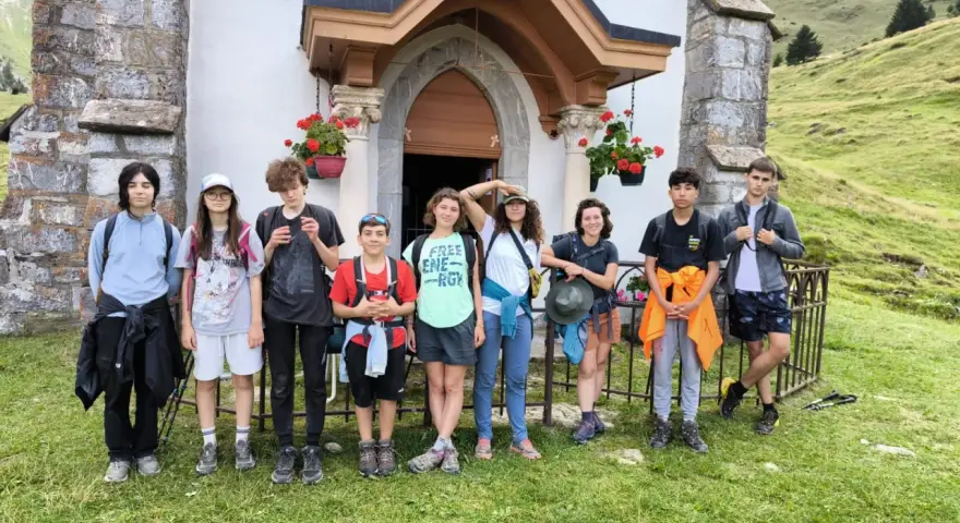 Groupe d'enfants en tenue de randonnée devant une petite église en montagne.