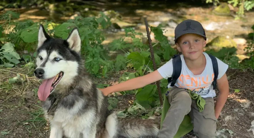 Un garçon et son husky profitent d'une aventure en pleine nature, un souvenir de leur colonie de vacances à l'étranger.