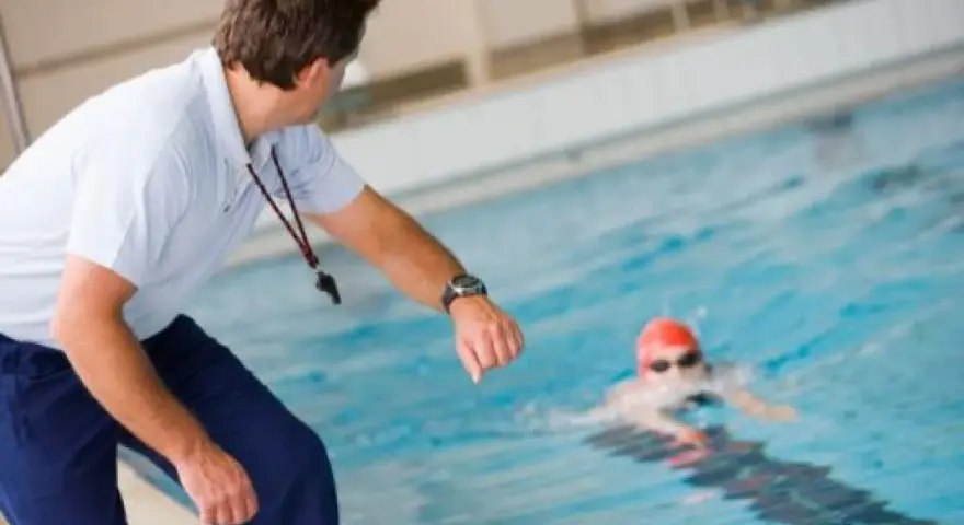 Entraîneur surveillant un nageur, peut-être pour un certificat de natation pour colonie.